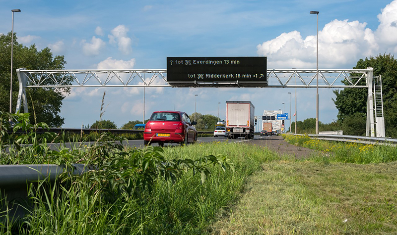 Een dynamisch route-informatiepaneel (DRIP) boven de A27. Het verkeer rijdt hieronderdoor.
